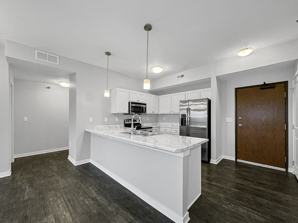 a white kitchen with a large island and a stainless steel refrigerator at Stonegate Crossing Apartments, Clive, IA, 50325