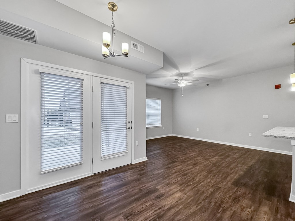 the living room and dining room of an apartment with wood flooring and white walls at Stonegate Crossing Apartments, IOWA, 50325