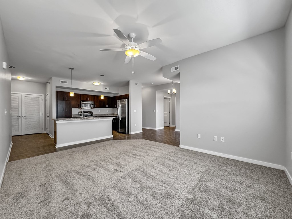 an empty living room and kitchen with a ceiling fan at Stonegate Crossing Apartments, Clive, 50325