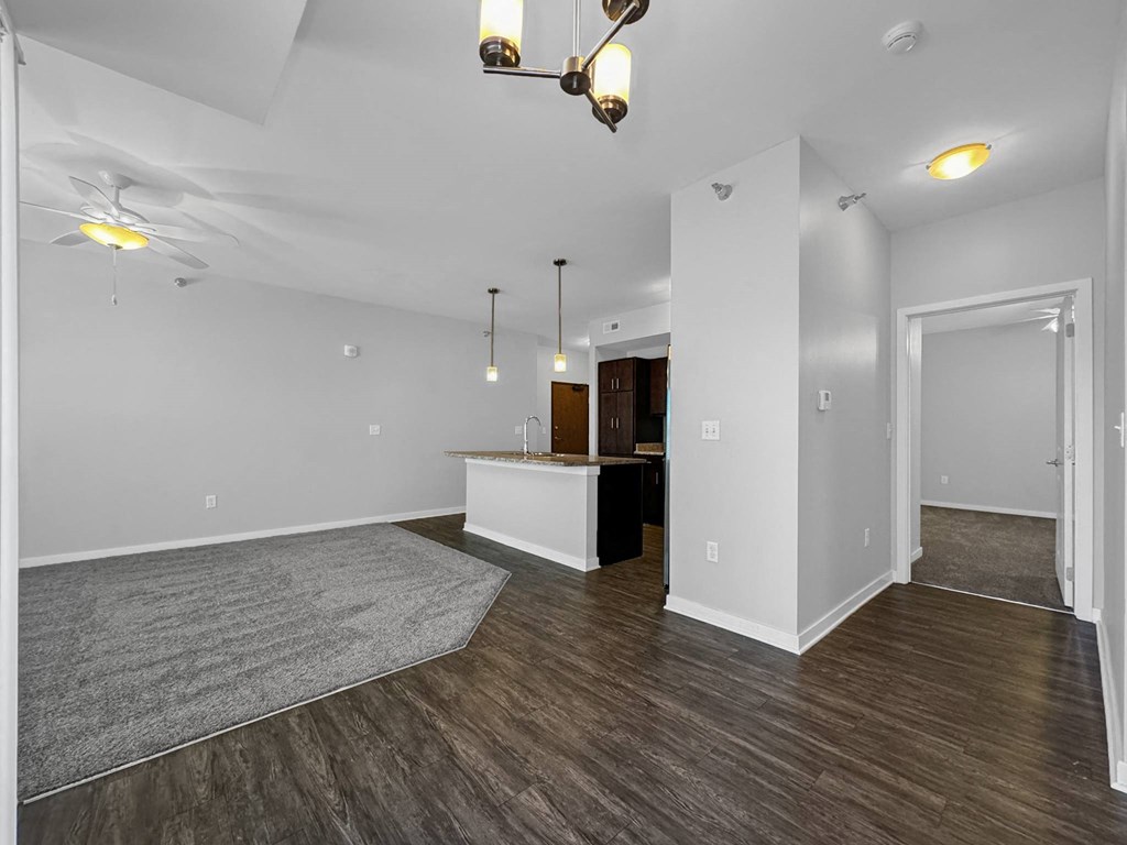the living room and kitchen of a new home with white walls and wood flooring at Stonegate Crossing Apartments, Clive, IA, 50325