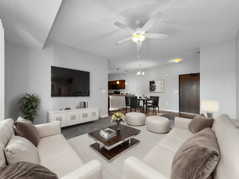 A modern living room with a white couch and a ceiling fan.