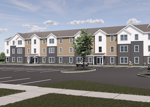 A modern apartment complex with a parking lot in front.