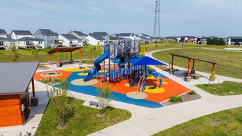 an aerial view of a colorful playground with houses in the background at Rialto Townhomes Apartments, Iowa, 50263