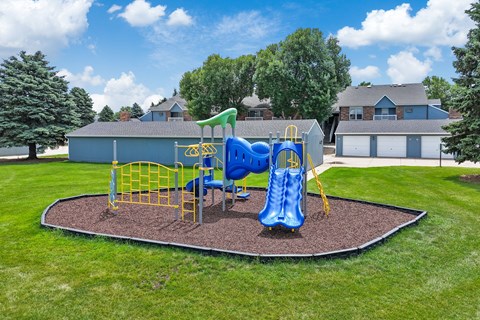 A playground with a blue slide and yellow safety barriers.