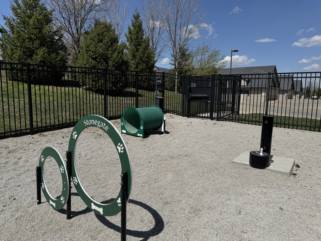 A playground with a green sign that says "Stonegate" and a green barrel.