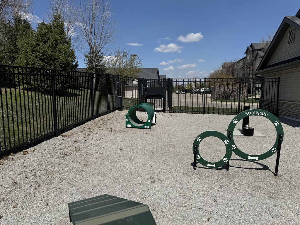 A playground with a green slide and a black fence.