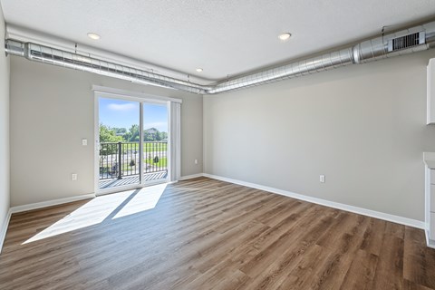 A room with wooden flooring and a sliding glass door leading to a patio.