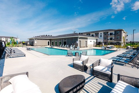 A large outdoor swimming pool area with lounge chairs and a building in the background.at Converge NW, Waukee, IA 50263  