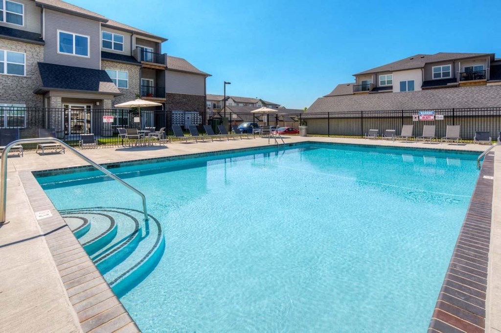 A swimming pool surrounded by a wooden deck and a fence. A swimming pool surrounded by a wooden deck and a fence. at Stonegate Crossing Apartments, IOWA