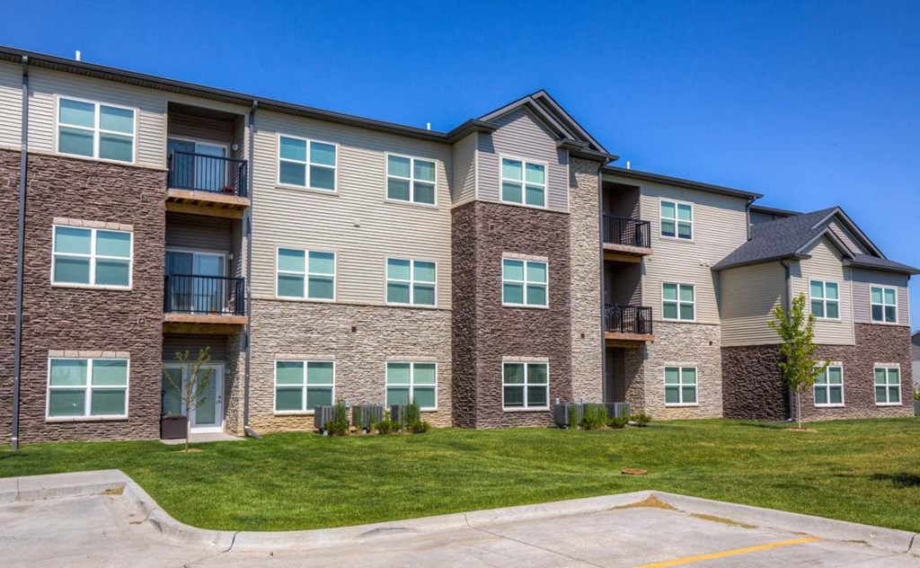 an exterior view of an apartment building with green grass at Stonegate Crossing Apartments, Clive, IOWA