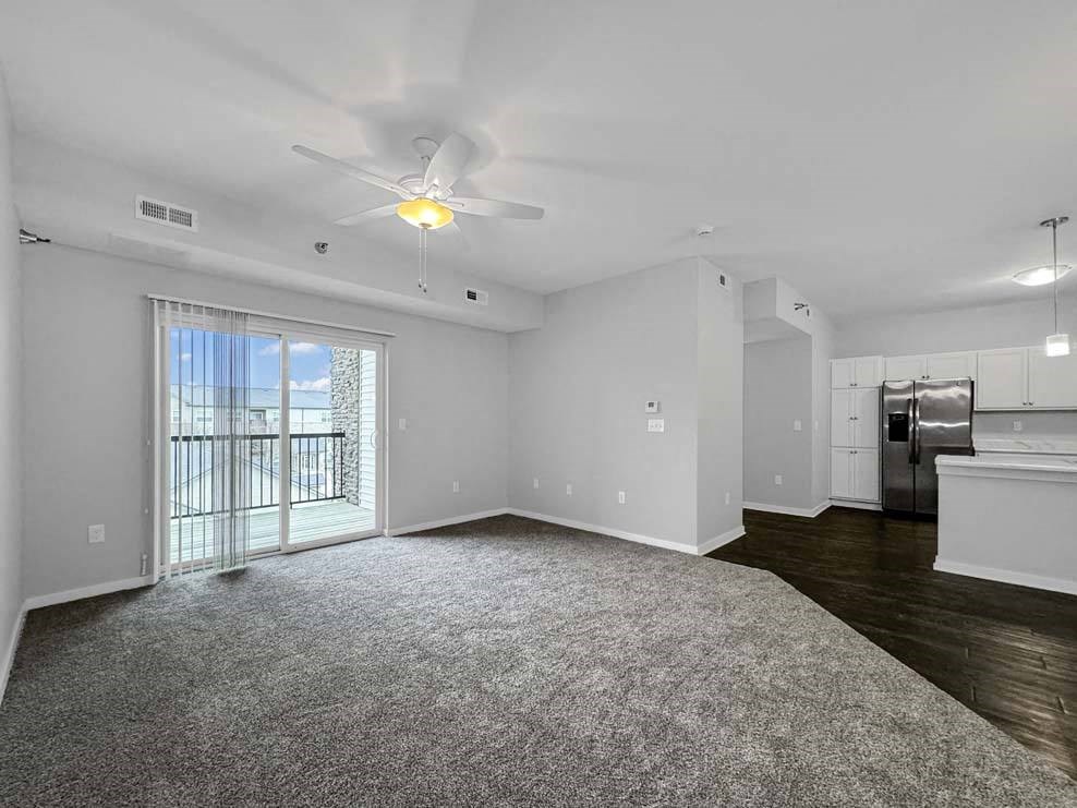 an empty living room with a ceiling fan and a window at Stonegate Crossing Apartments, Clive, IOWA