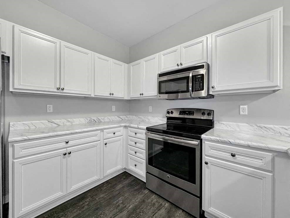 A kitchen with white cabinets and a black stove top oven. at Stonegate Crossing Apartments, Clive