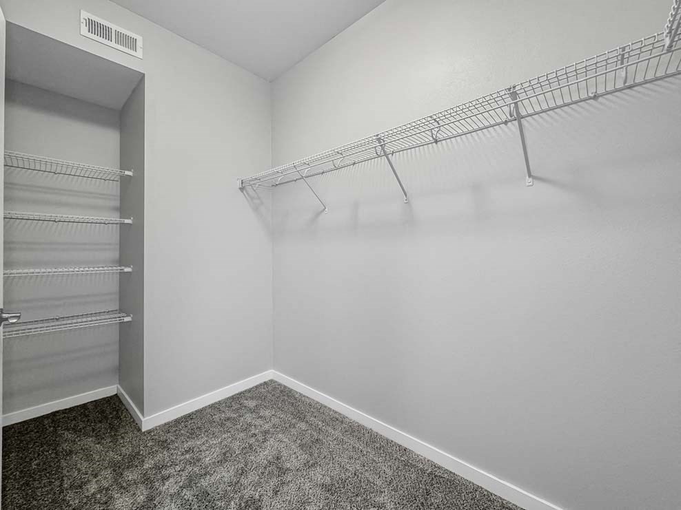 a closet in a white room with a mirrored closet door at Stonegate Crossing Apartments, IOWA