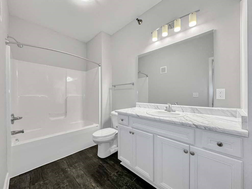 A white bathroom with a toilet, sink, and shower at Stonegate Crossing Apartments, Clive, IA, 50325