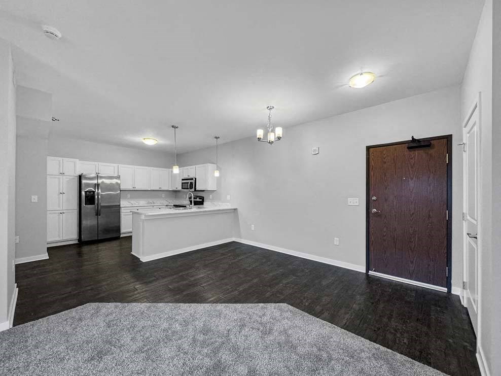 A kitchen with white cabinets and a refrigerator is visible. at Stonegate Crossing Apartments, Clive, IA, 50325