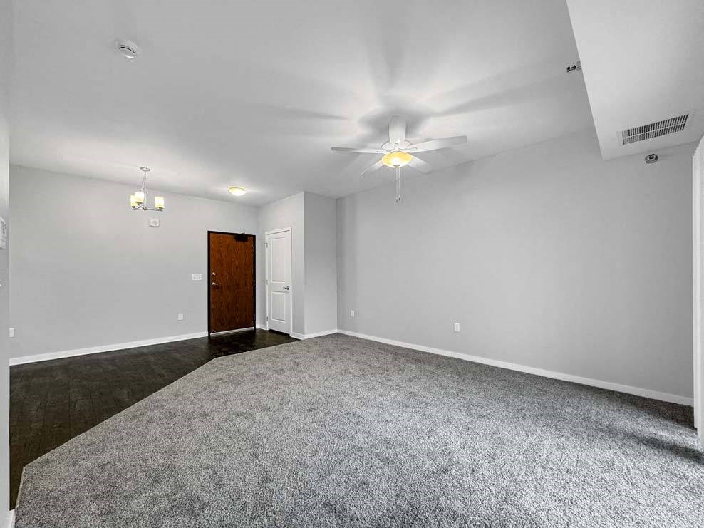 A room with a carpeted floor and a ceiling fan. at Stonegate Crossing Apartments, IOWA