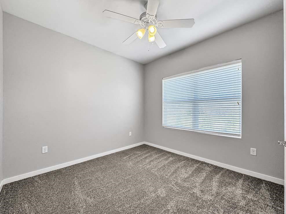 an empty bedroom with a ceiling fan and a window at Stonegate Crossing Apartments, IOWA, 50325