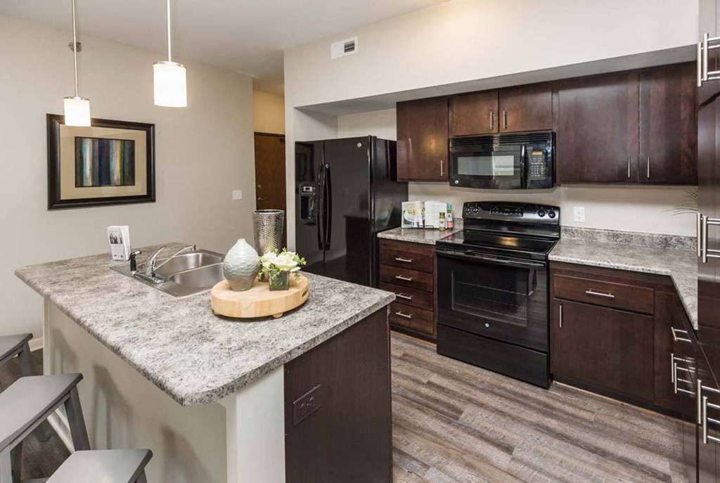 a kitchen with black appliances and a granite counter top at Stonegate Crossing Apartments, Clive