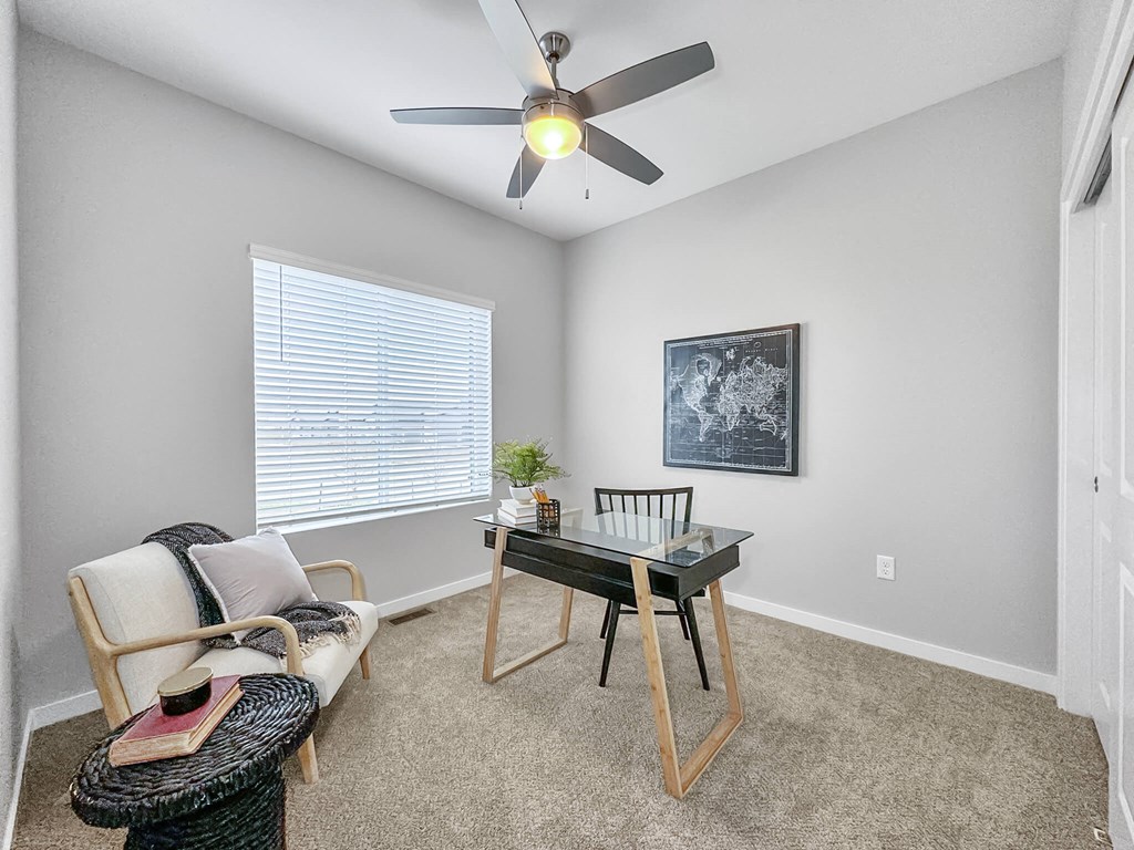 a room with a desk and a ceiling fan at Rialto Townhomes Apartments, Waukee, IA, 50263