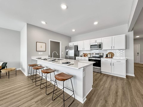 A modern kitchen with white cabinets and a long island.