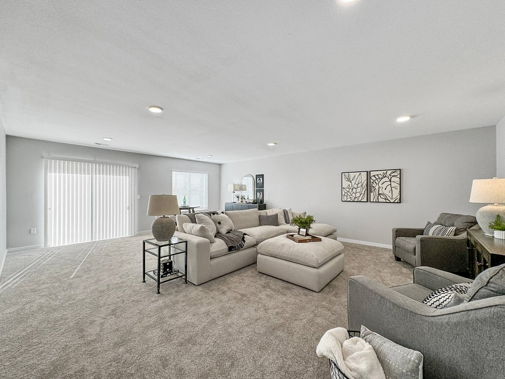 a living room with couches and chairs and a large window at Rialto Townhomes Apartments, Waukee, IA