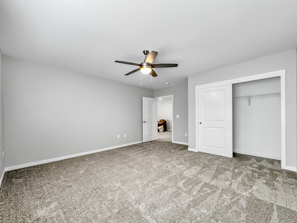 an empty living room with a ceiling fan and a closet at Rialto Townhomes Apartments, Waukee, Iowa