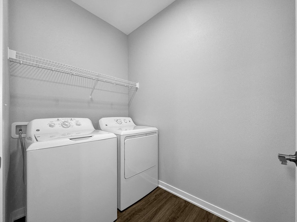a washer and dryer in a room with a white wall and a shelf at Rialto Townhomes Apartments, Iowa, 50263