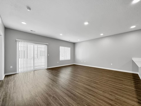 an empty living room with wood flooring and a window at Rialto Townhomes Apartments, Waukee