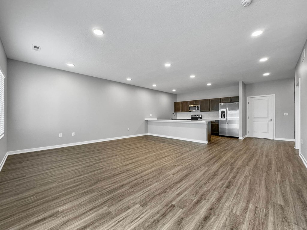 the living room and kitchen of a new home with wood flooring at Rialto Townhomes Apartments, Waukee, IA