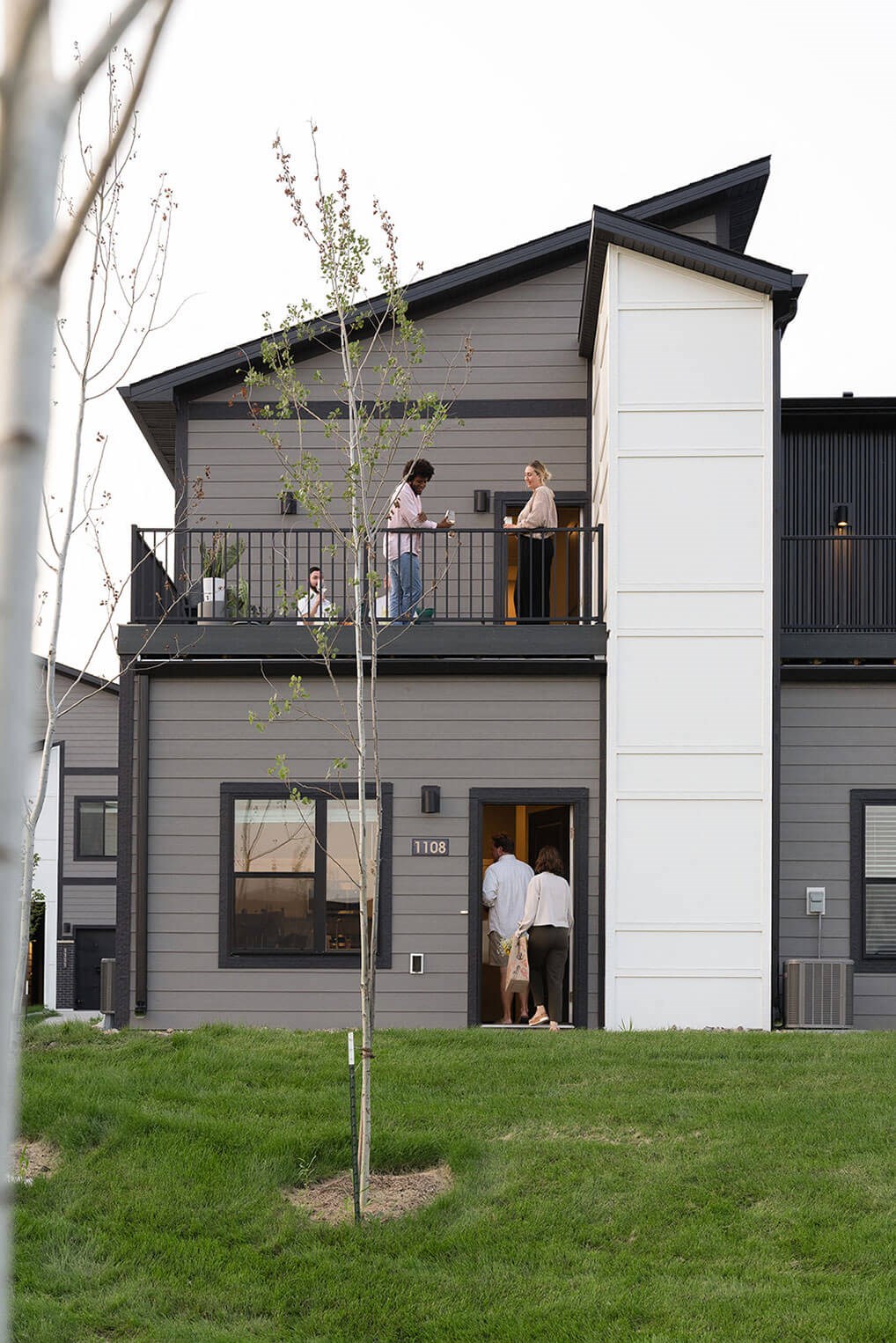 people standing on the balcony of a gray house at Rialto Townhomes Apartments, Waukee