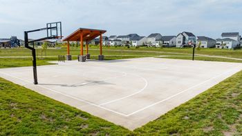 a basketball court in a park with houses in the background at Rialto Townhomes Apartments, Waukee, IA