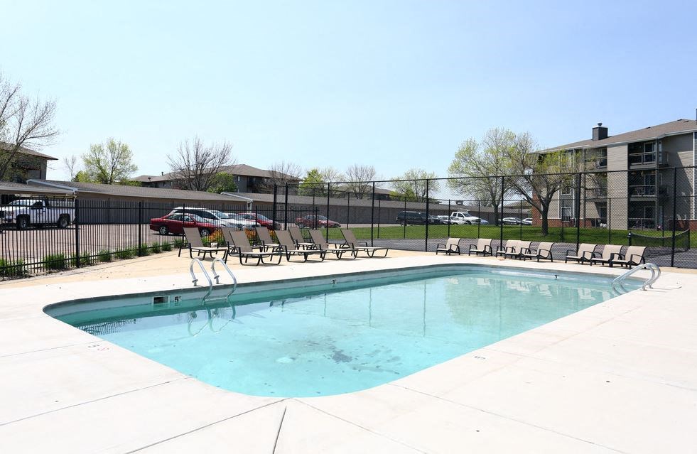 a swimming pool with chairs and a fence around it at Penbrooke Place Apartments, Sioux Falls, SD