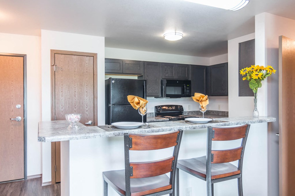 A kitchen with a black refrigerator, black microwave, and black oven at Penbrooke Place Apartments, South Dakota, 57106