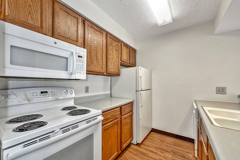 A kitchen with white appliances and wooden cabinets at Penbrooke Place Apartments, Sioux Falls, South Dakota