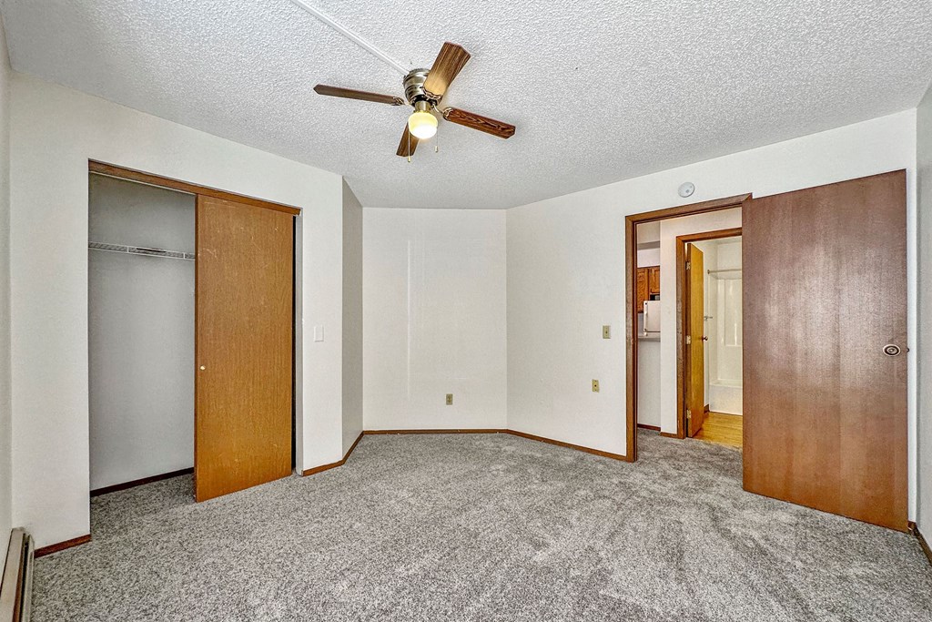 an empty living room with a ceiling fan and a door to a closet at Penbrooke Place Apartments, South Dakota, 57106