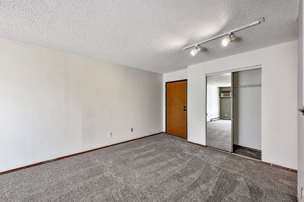 A room with a carpeted floor and a wooden door at Penbrooke Place Apartments, Sioux Falls, SD, 57106
