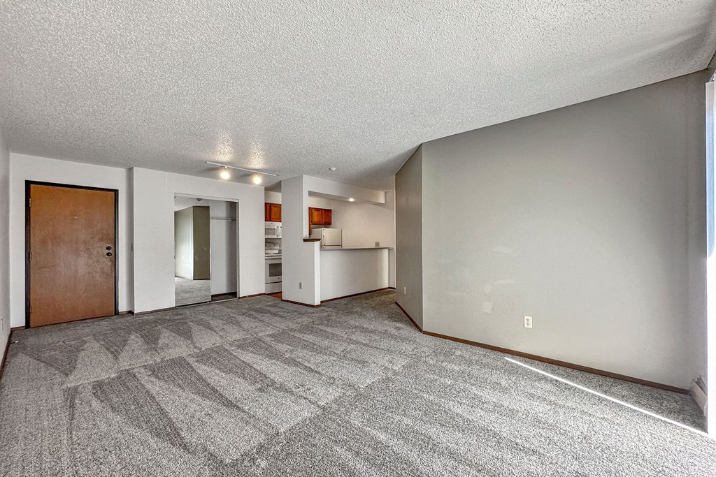 the living room and kitchen of an apartment with a carpeted floor at Penbrooke Place Apartments, South Dakota