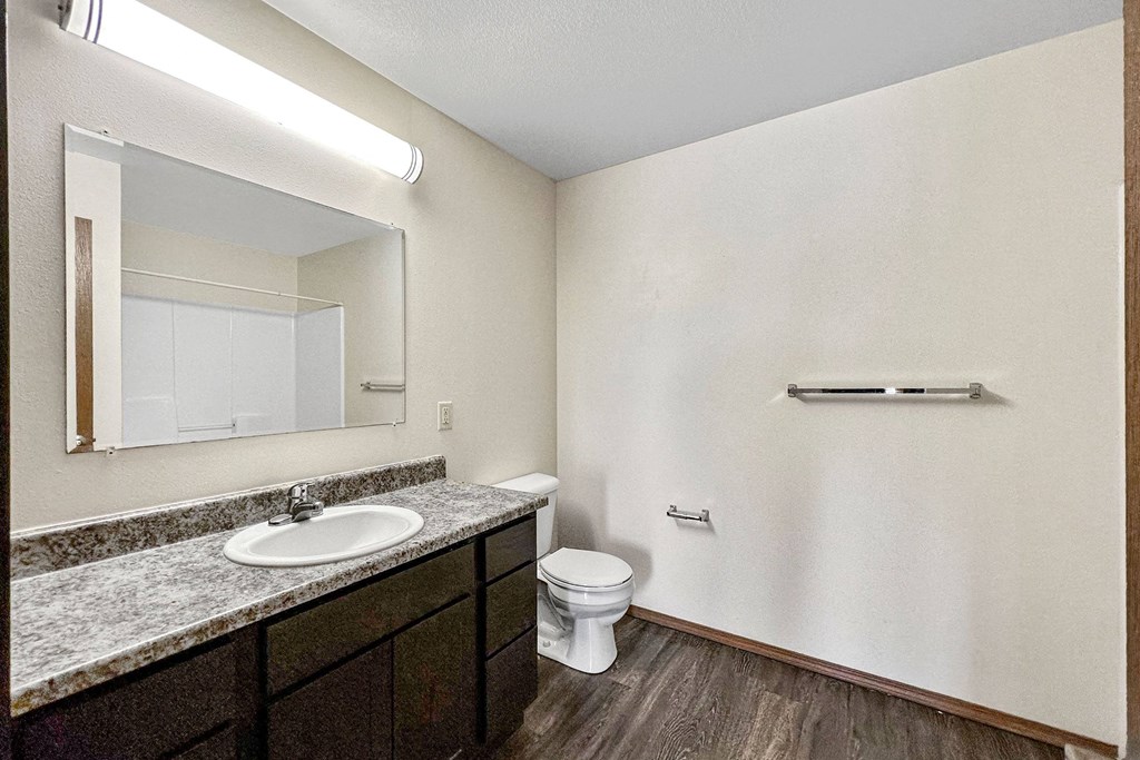 A bathroom with a sink, toilet, and mirror at Penbrooke Place Apartments, Sioux Falls