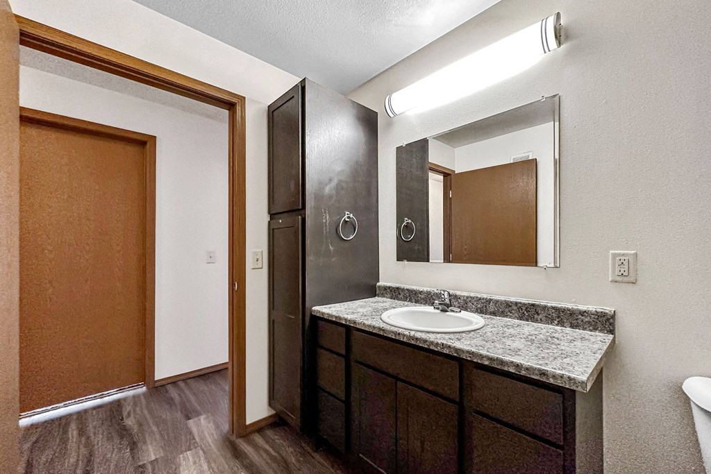 A bathroom with a sink, mirror, and toilet at Penbrooke Place Apartments, Sioux Falls, South Dakota