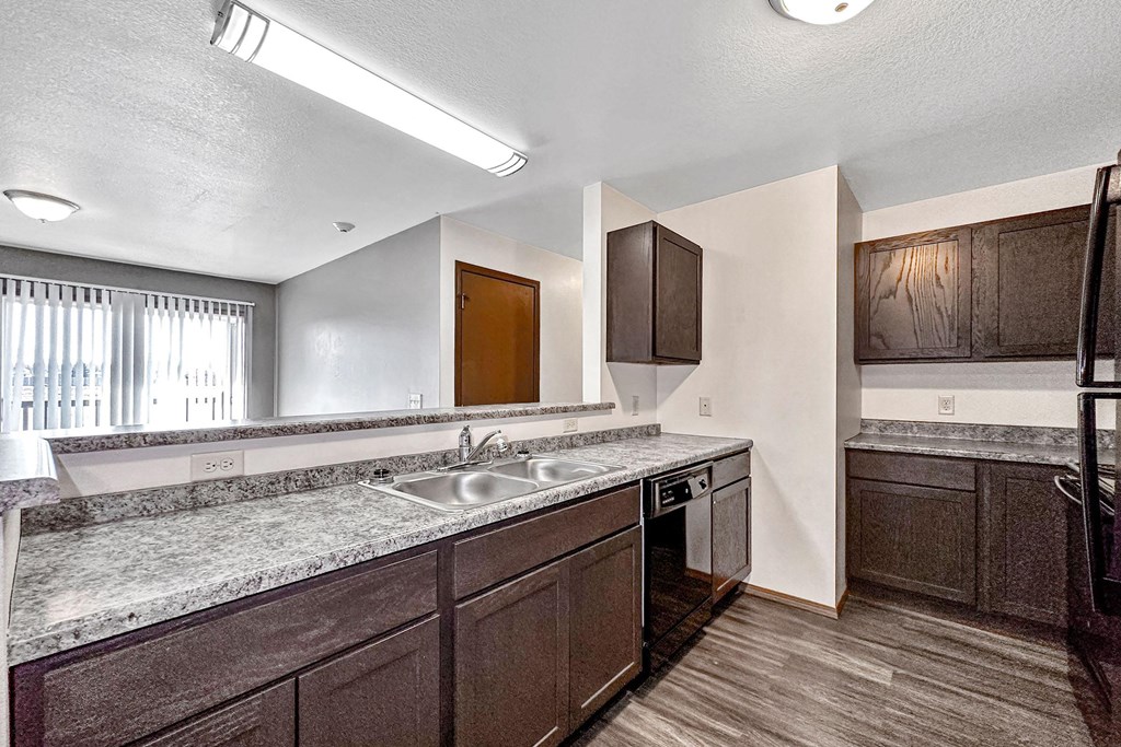 a kitchen with granite counter tops and a stainless steel sink at Penbrooke Place Apartments, South Dakota