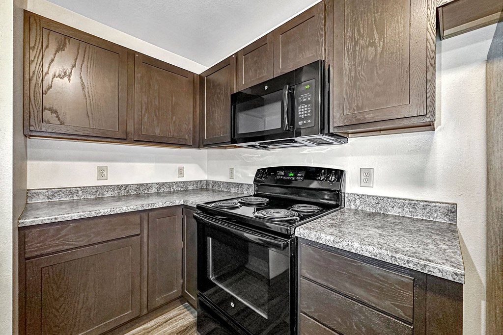 a kitchen with black appliances and wood cabinets at Penbrooke Place Apartments, South Dakota, 57106