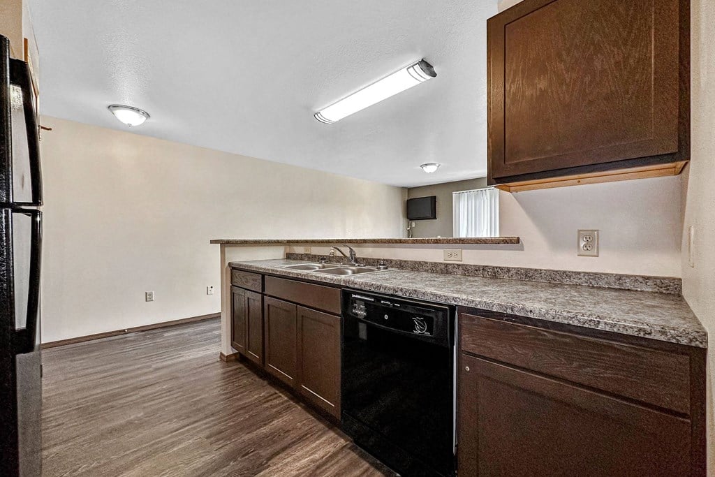 A kitchen with a black oven and wooden cabinets at Penbrooke Place Apartments, Sioux Falls, 57106