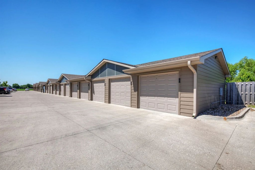 A row of houses with garages are lined up in a parking lot.