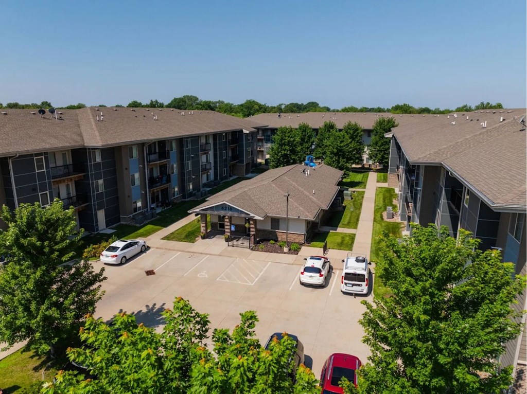 A parking lot in front of a building with cars parked.