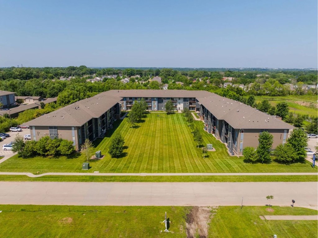 A large, modern building with a long, wide lawn in front.