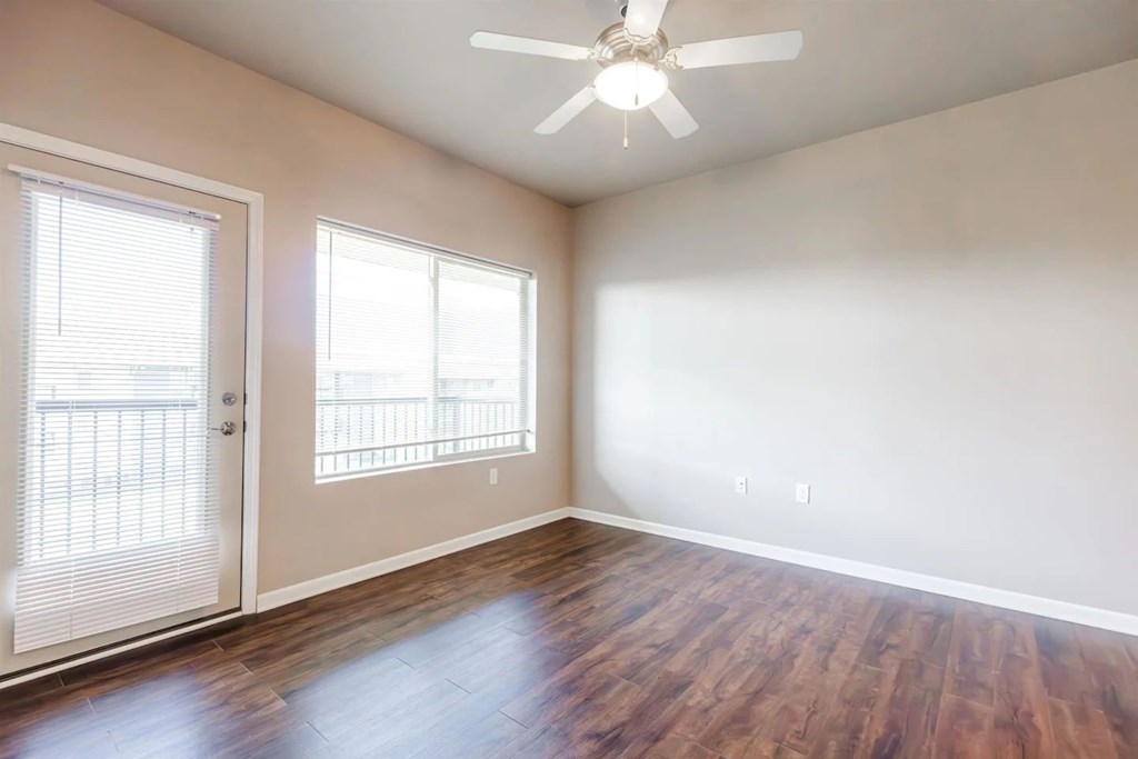 A room with a ceiling fan and wooden flooring.