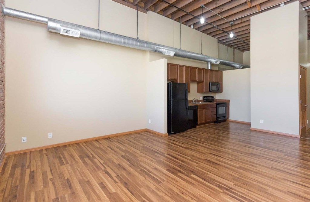 A kitchen area with wooden floors and a black refrigerator.at Riverpoint Lofts, Des Moines, IA  