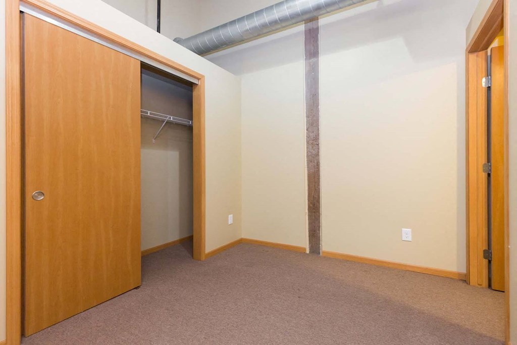 A room with a brown carpet and a wooden door.at Riverpoint Lofts, Iowa   