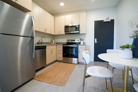 A modern kitchen with a stainless steel refrigerator and a white table with a plant on it.