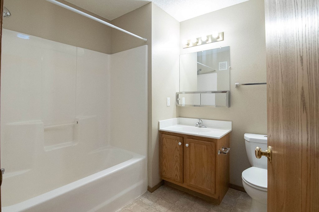 A bathroom with a white tub, sink, and toilet at Peach Tree Apartments, IA, 50021